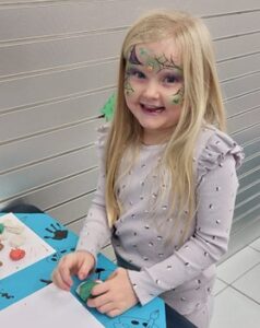 Young child presses different colours of plasticine firmly together to represent being included